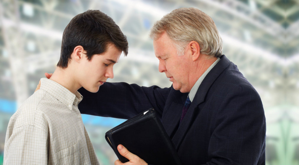 preacher leading the young man in prayer